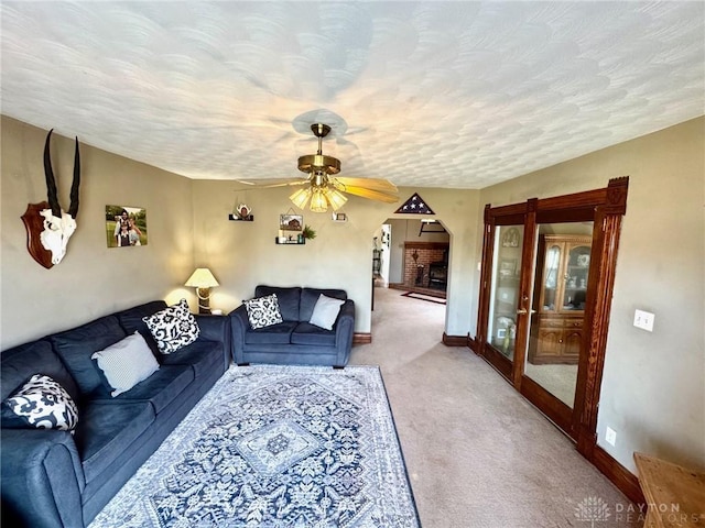 carpeted living room featuring ceiling fan and a textured ceiling