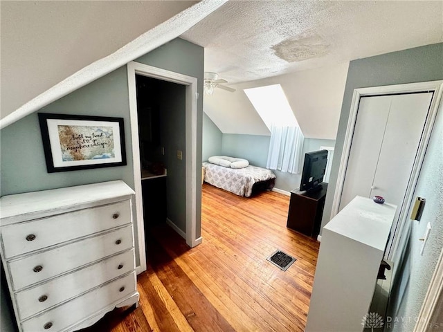 bedroom featuring lofted ceiling, a textured ceiling, and light hardwood / wood-style flooring