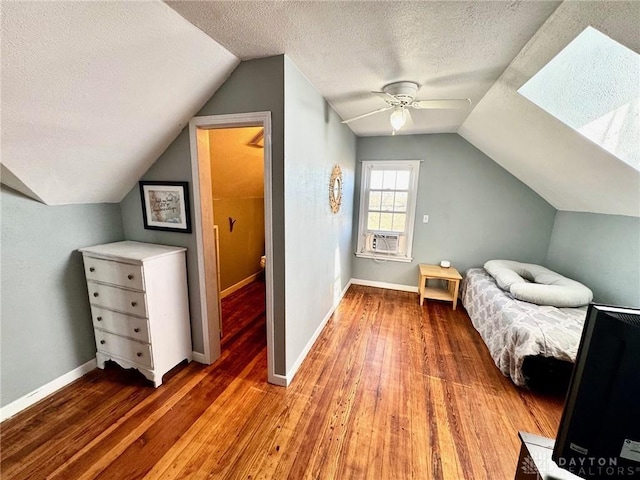 bedroom with ceiling fan, vaulted ceiling, hardwood / wood-style floors, and a textured ceiling