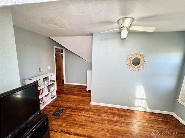 living room with ceiling fan, vaulted ceiling, dark hardwood / wood-style floors, and a textured ceiling