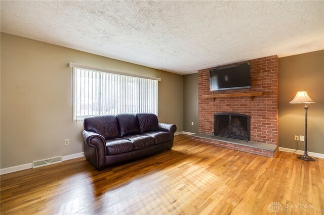 living room featuring a fireplace, wood-type flooring, and a textured ceiling