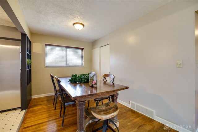 dining area with wood-type flooring and a textured ceiling