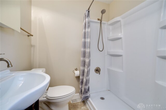 bathroom featuring tile patterned flooring, sink, toilet, and walk in shower