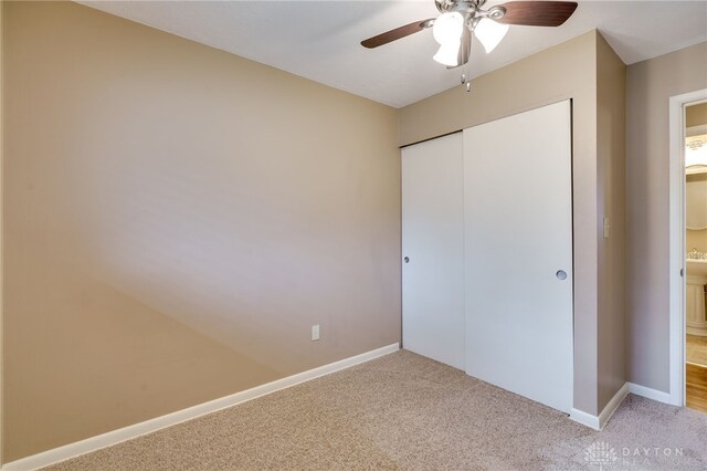 unfurnished bedroom with light colored carpet, a closet, and ceiling fan