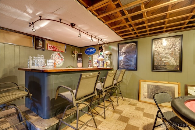 bar featuring rail lighting and wood walls