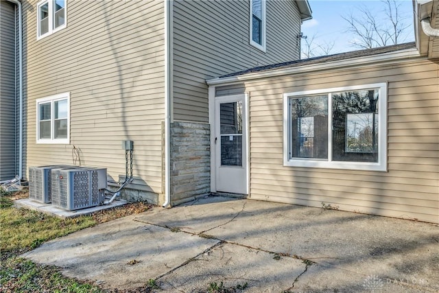 view of exterior entry with central AC and a patio area