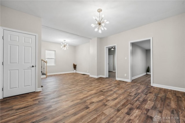 empty room featuring dark wood-type flooring and an inviting chandelier