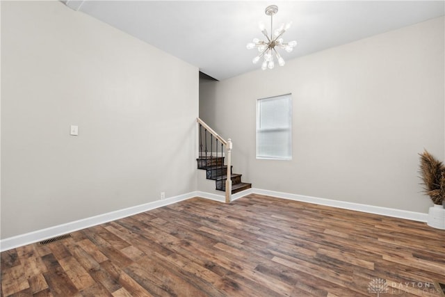 spare room featuring hardwood / wood-style floors and an inviting chandelier