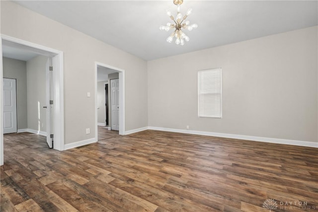 spare room featuring dark hardwood / wood-style floors and an inviting chandelier