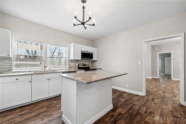 kitchen with sink, hanging light fixtures, stainless steel appliances, tasteful backsplash, and white cabinets