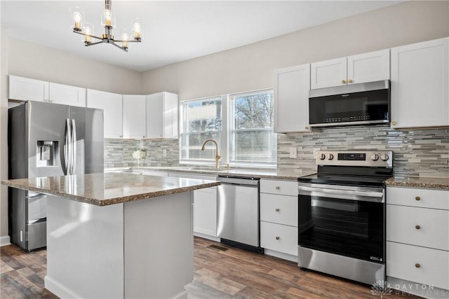 kitchen with pendant lighting, a center island, dark wood-type flooring, white cabinetry, and stainless steel appliances