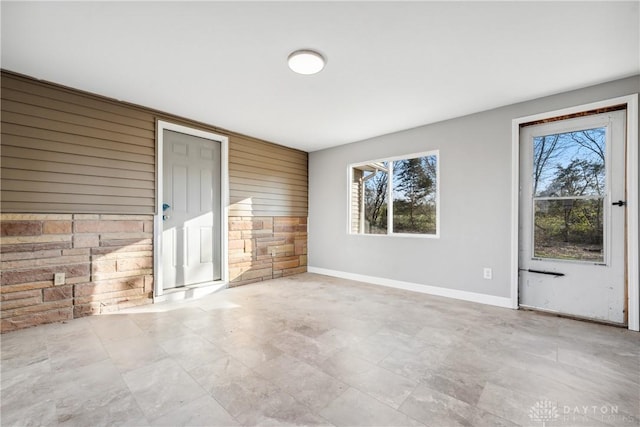 unfurnished living room with plenty of natural light and wooden walls