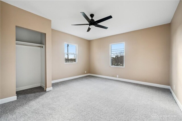 unfurnished bedroom featuring multiple windows, ceiling fan, and carpet