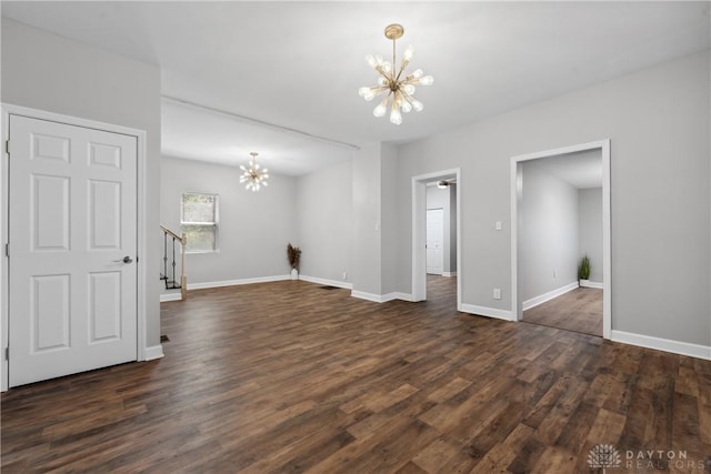 unfurnished living room featuring baseboards, an inviting chandelier, dark wood-type flooring, and stairway