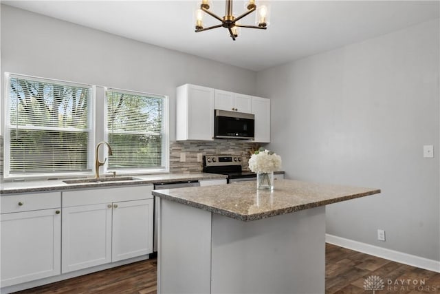 kitchen featuring a sink, decorative backsplash, appliances with stainless steel finishes, dark wood finished floors, and a notable chandelier