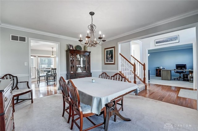 dining room featuring crown molding, light hardwood / wood-style floors, and an inviting chandelier