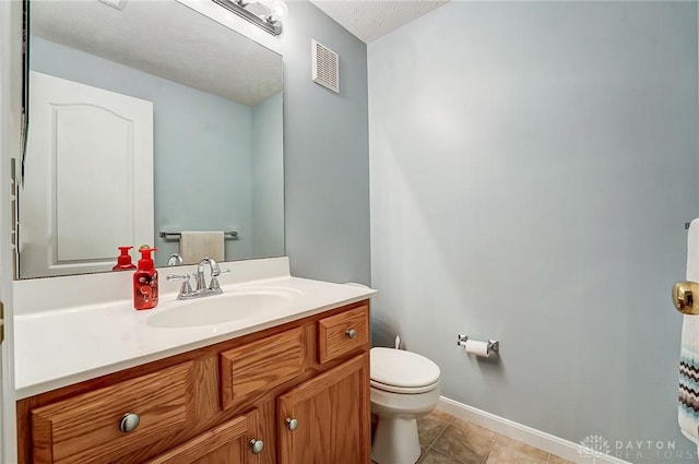 bathroom featuring tile patterned flooring, vanity, a textured ceiling, and toilet