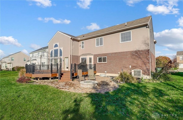 rear view of property with a yard, a fire pit, a wooden deck, cooling unit, and a patio