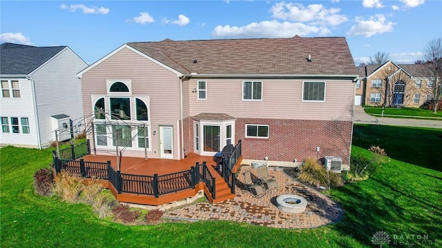 back of property featuring a lawn, a wooden deck, cooling unit, and a fire pit