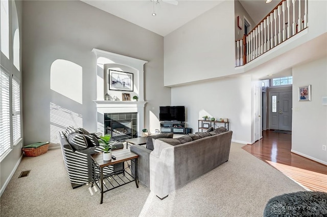 living room featuring a fireplace, a high ceiling, hardwood / wood-style flooring, and ceiling fan