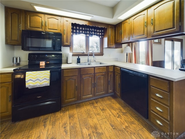 kitchen featuring kitchen peninsula, sink, black appliances, and dark hardwood / wood-style flooring