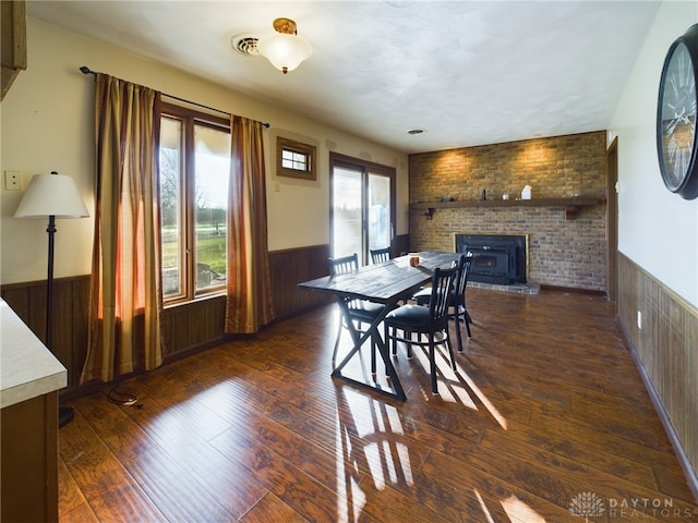 dining room featuring wood walls, dark wood-type flooring, and brick wall