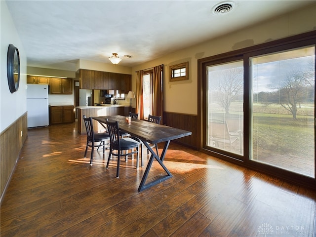 dining space featuring dark hardwood / wood-style floors, a healthy amount of sunlight, and wooden walls