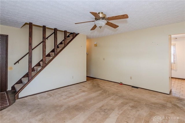 unfurnished living room featuring ceiling fan, light colored carpet, and a textured ceiling