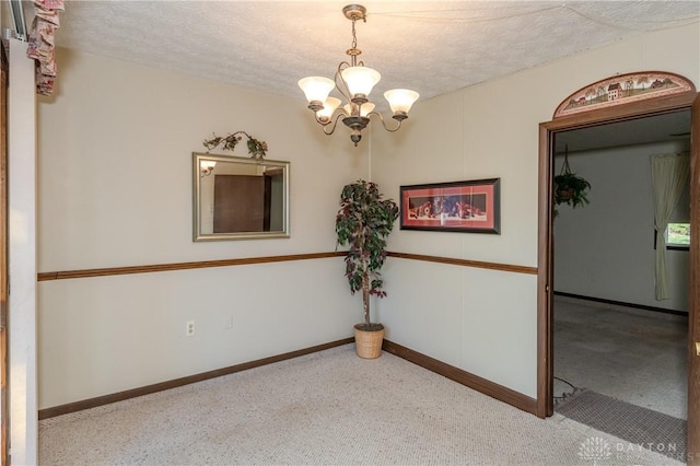 spare room featuring a textured ceiling and a notable chandelier