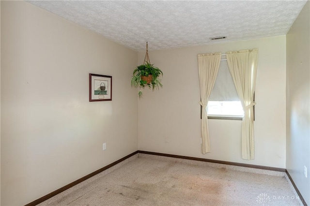 spare room with a textured ceiling and light colored carpet