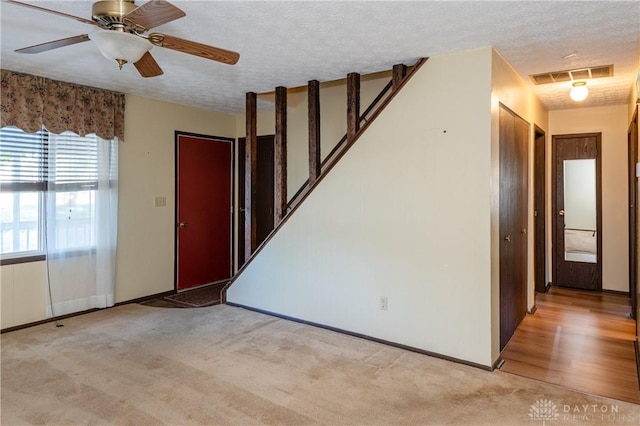 carpeted foyer featuring ceiling fan and a textured ceiling