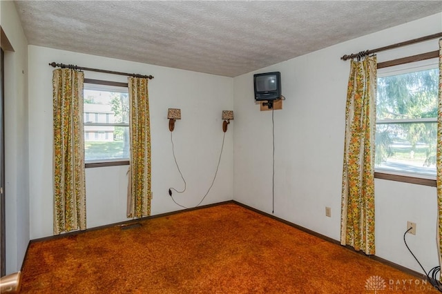 carpeted empty room featuring a textured ceiling