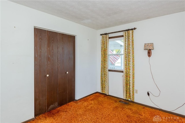 unfurnished bedroom with carpet, a textured ceiling, and a closet