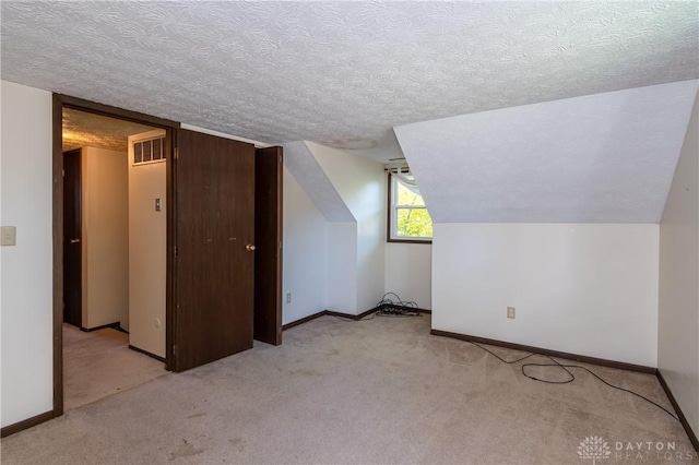 bonus room featuring lofted ceiling, a textured ceiling, and light carpet