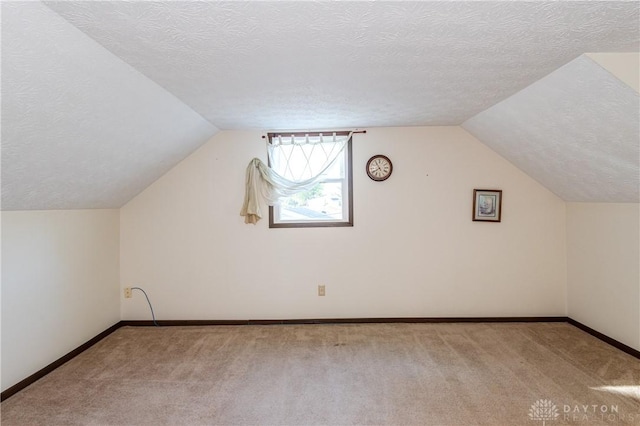 bonus room featuring vaulted ceiling, light carpet, and a textured ceiling