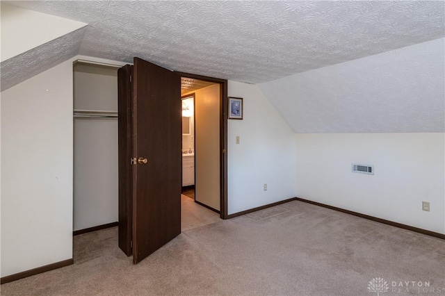 additional living space featuring light carpet, a textured ceiling, and vaulted ceiling