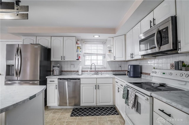 kitchen with white cabinets, sink, decorative backsplash, light tile patterned flooring, and stainless steel appliances