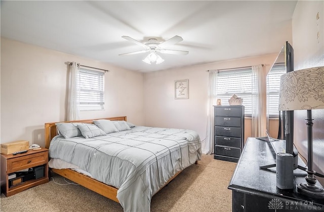 carpeted bedroom featuring multiple windows and ceiling fan