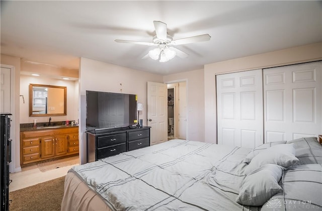 carpeted bedroom with connected bathroom, ceiling fan, a closet, and sink