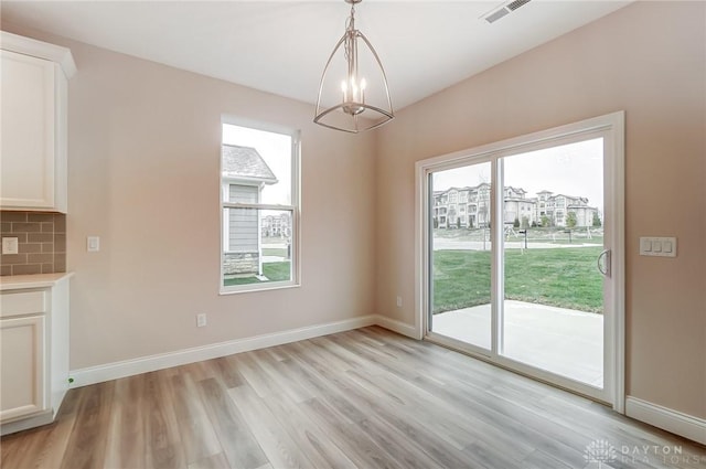 unfurnished dining area with light wood-type flooring and an inviting chandelier