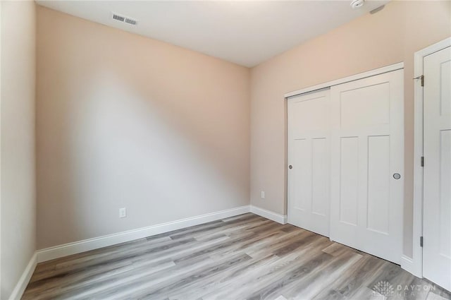 unfurnished bedroom with light hardwood / wood-style flooring and a closet