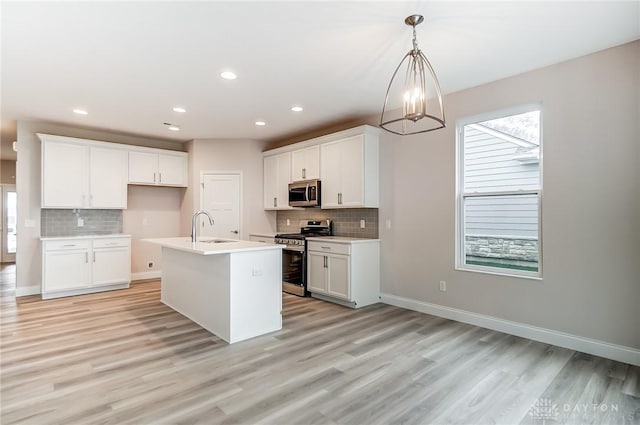 kitchen with a center island with sink, white cabinets, stainless steel appliances, and light hardwood / wood-style flooring