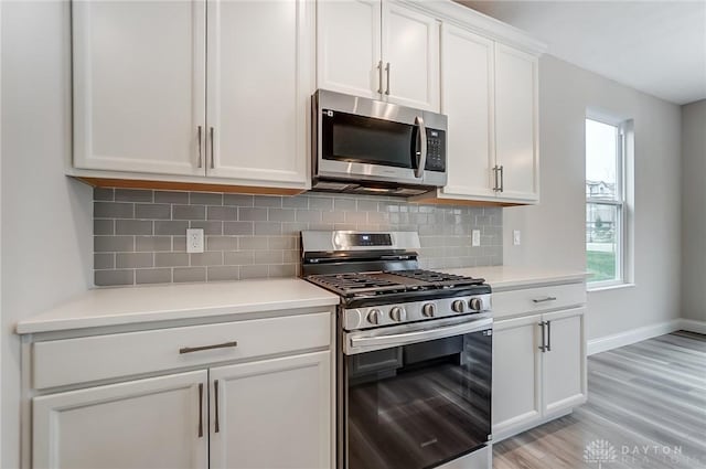 kitchen featuring tasteful backsplash, a wealth of natural light, white cabinets, and appliances with stainless steel finishes