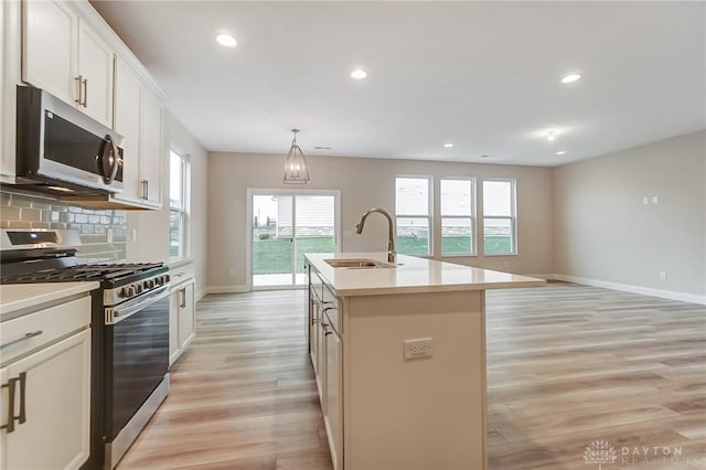 kitchen featuring appliances with stainless steel finishes, light wood-type flooring, a kitchen island with sink, sink, and white cabinetry