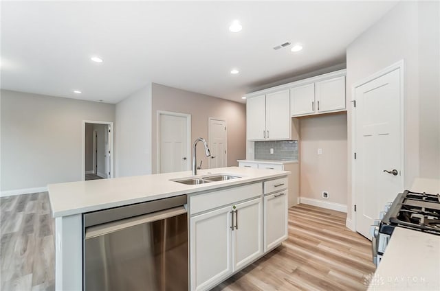 kitchen featuring white cabinets, gas range oven, sink, a center island with sink, and dishwasher