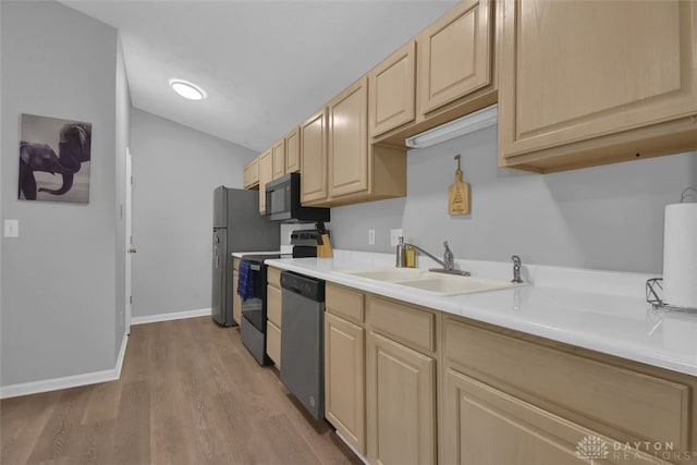 kitchen with light brown cabinetry, sink, stainless steel appliances, and light hardwood / wood-style floors