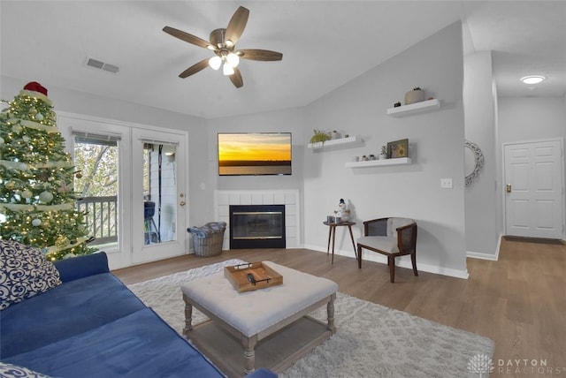 living room with a fireplace, hardwood / wood-style floors, vaulted ceiling, and ceiling fan