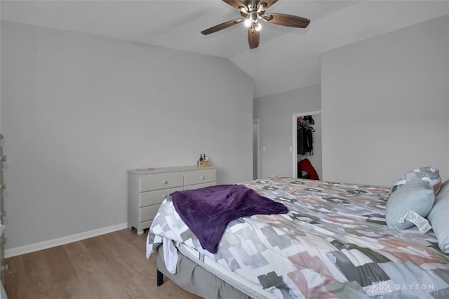 bedroom featuring ceiling fan, a spacious closet, lofted ceiling, a closet, and light wood-type flooring