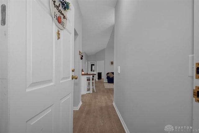 corridor featuring light hardwood / wood-style floors and vaulted ceiling