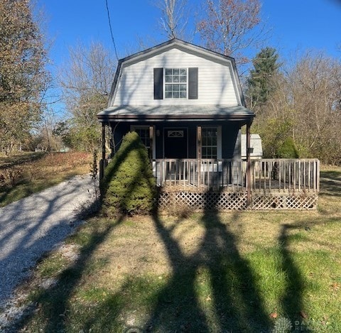 dutch colonial featuring a porch, a front lawn, and a gambrel roof